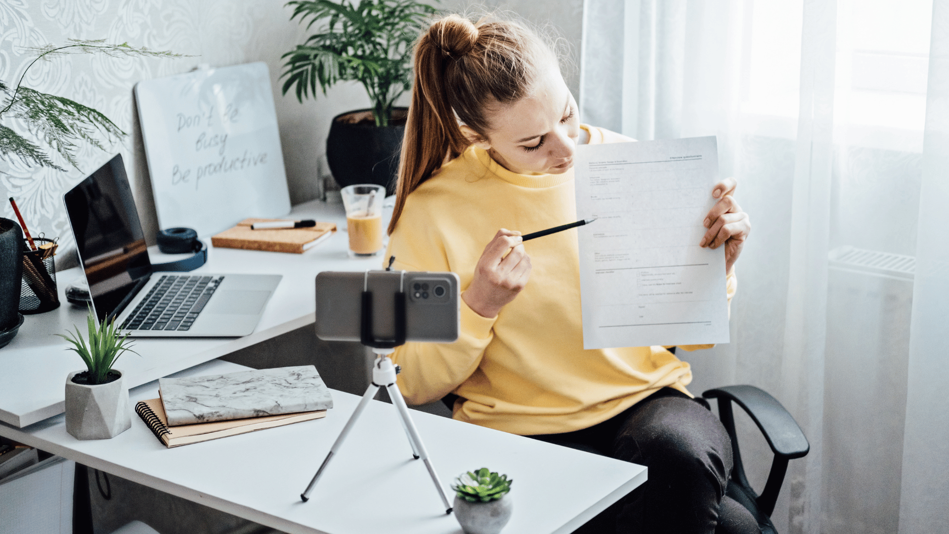 Mulher trabalhando em home office gravando vídeo com dicas de renda extra, mostrando documento para ganhar dinheiro online.